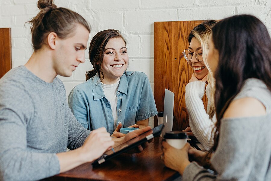 Studierende die sich an einem Tisch über Inhalte austauschen